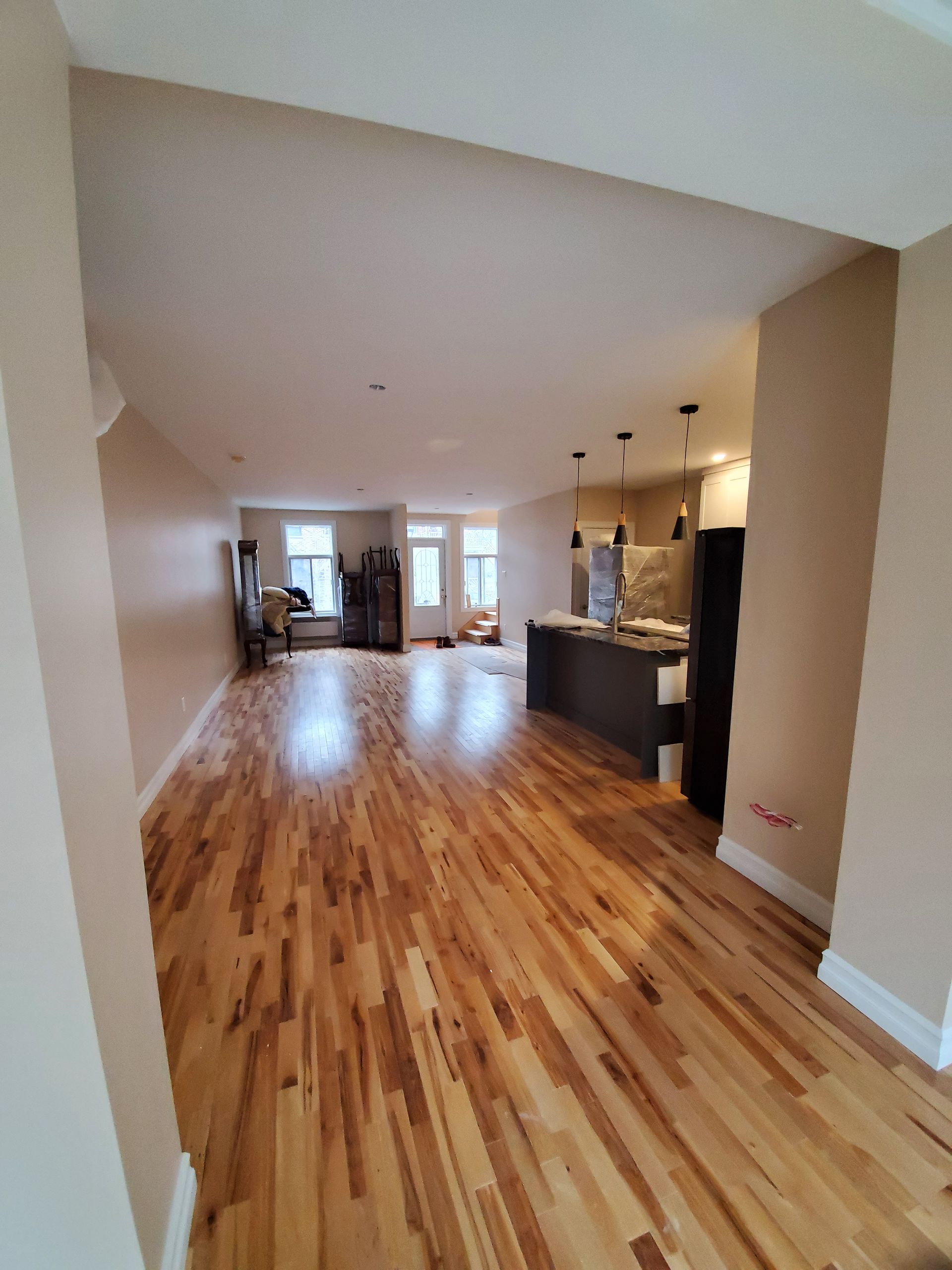 Un salon avec parquet et une cuisine en arrière-plan