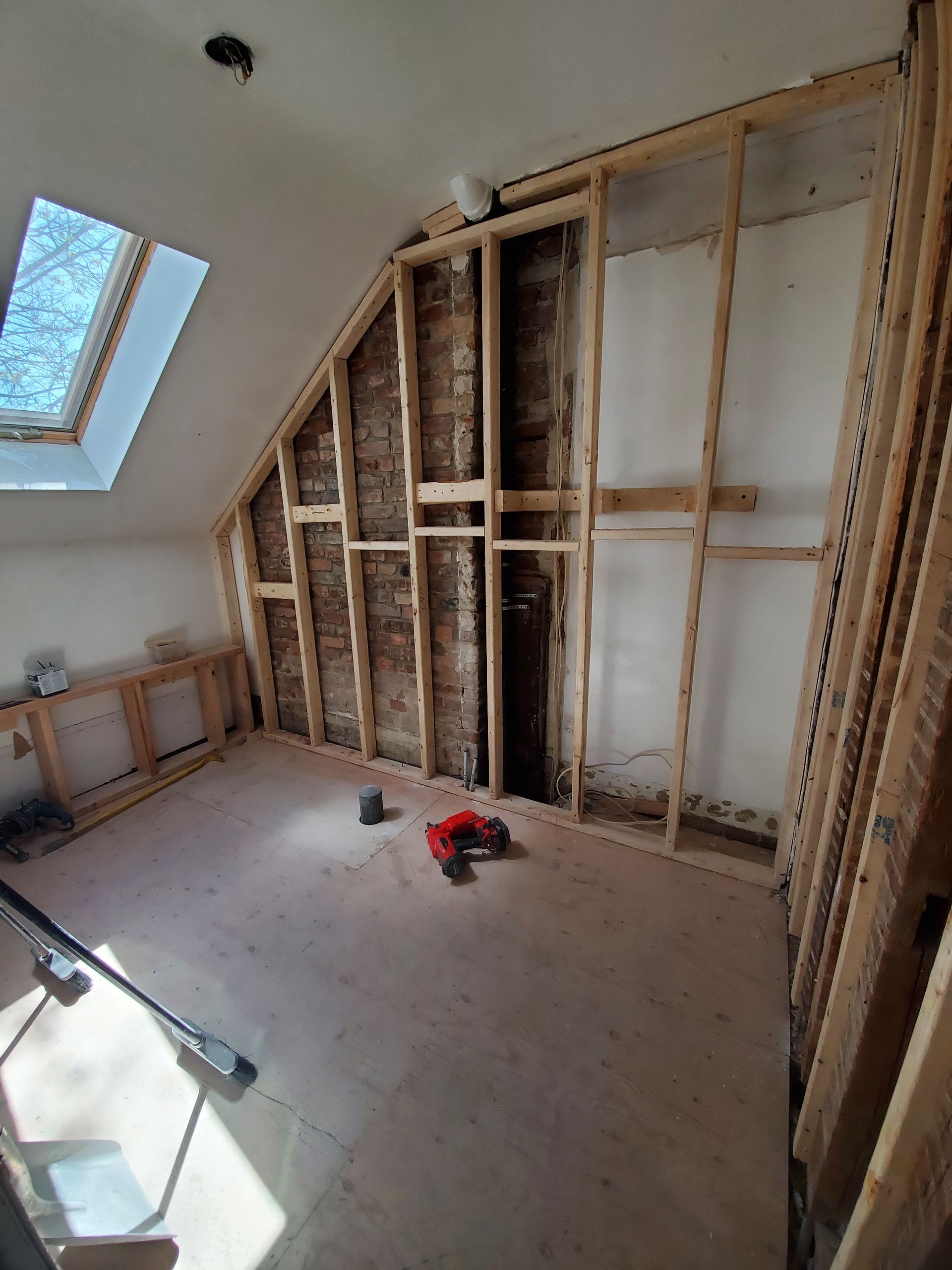 Une pièce avec un mur de briques et une lucarne au plafond.