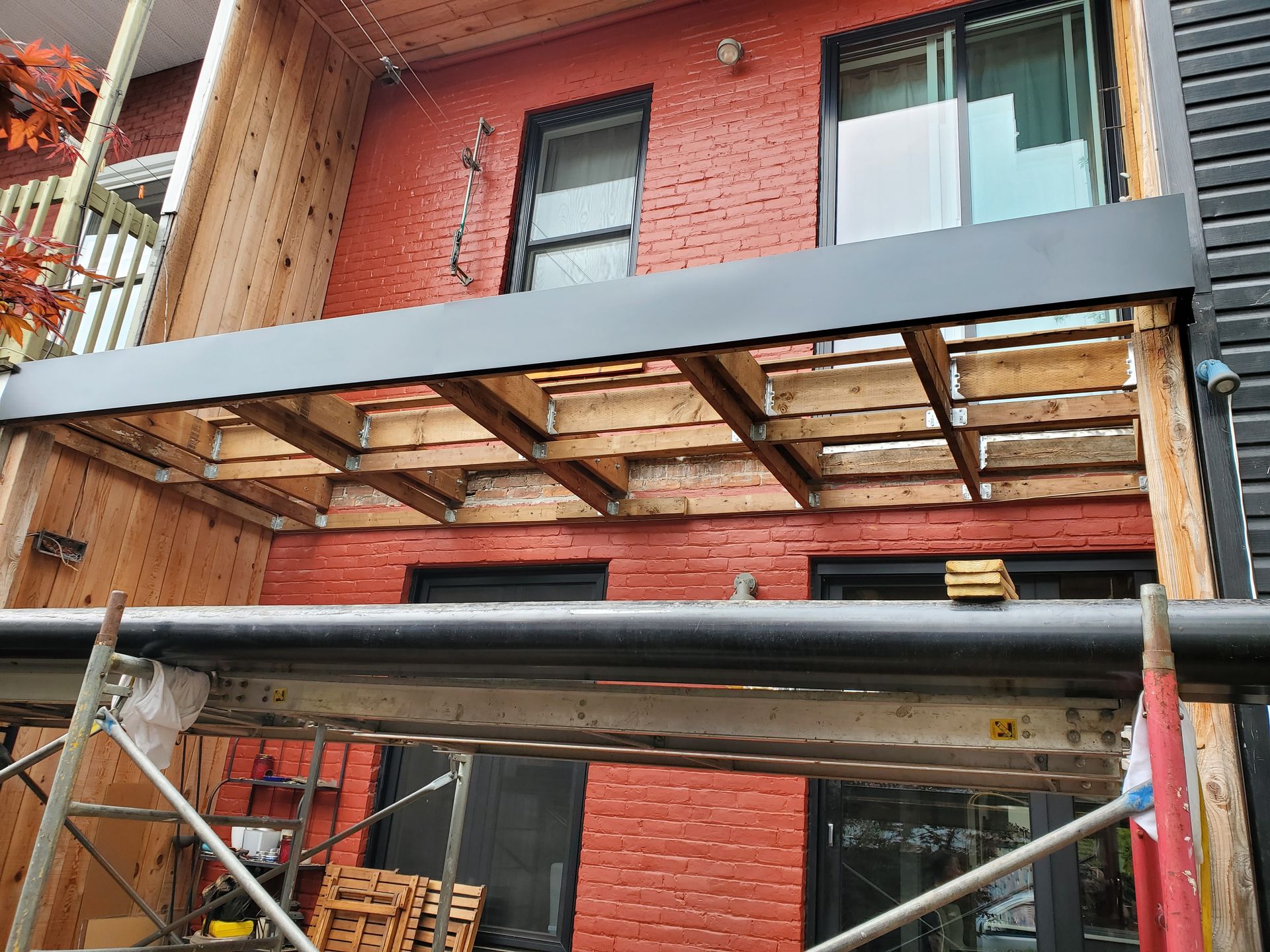 Une terrasse en bois est en cours de construction sur le côté d'un bâtiment en brique.