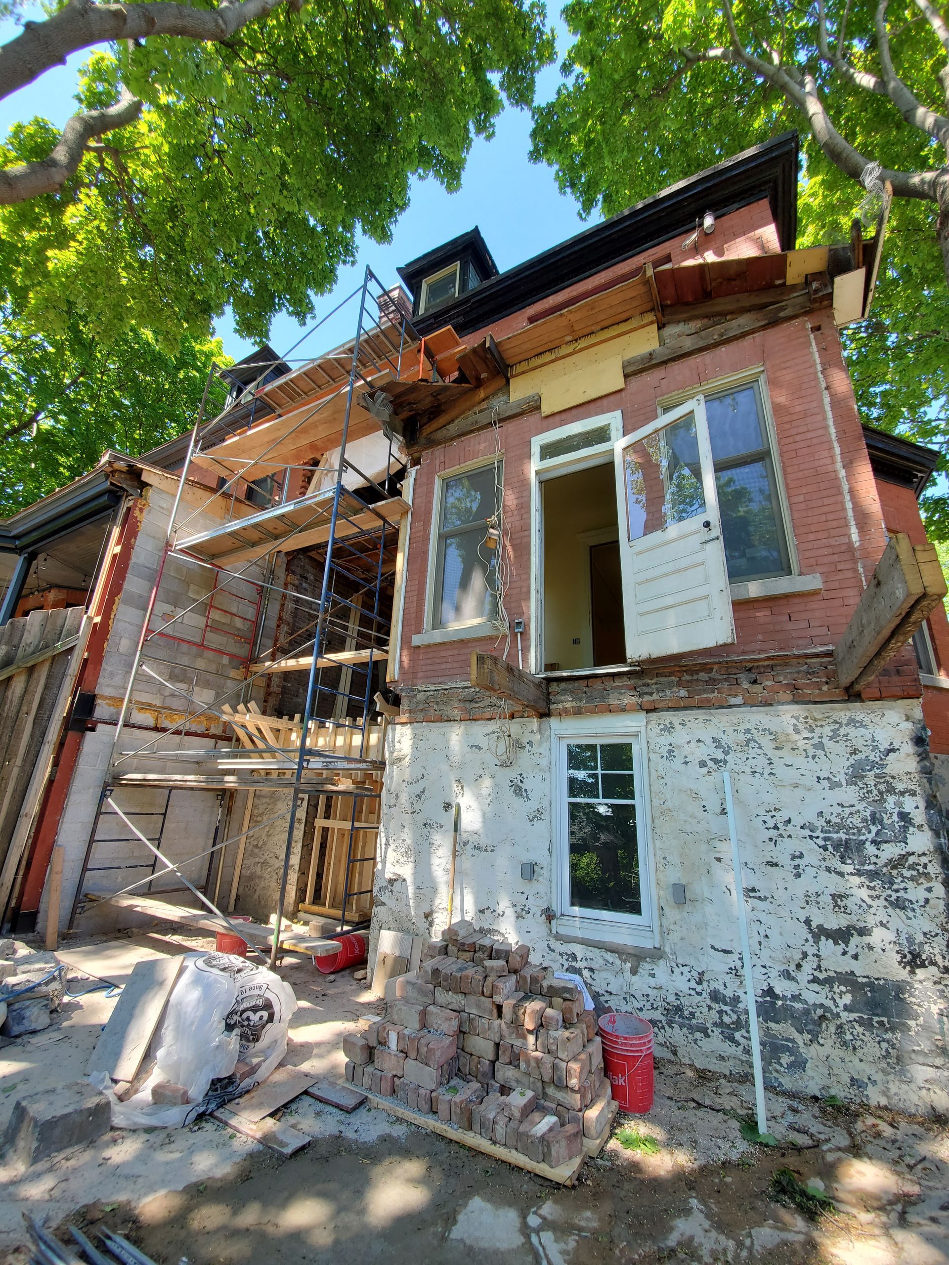 Une maison en brique est en cours de rénovation avec des échafaudages et des briques.
