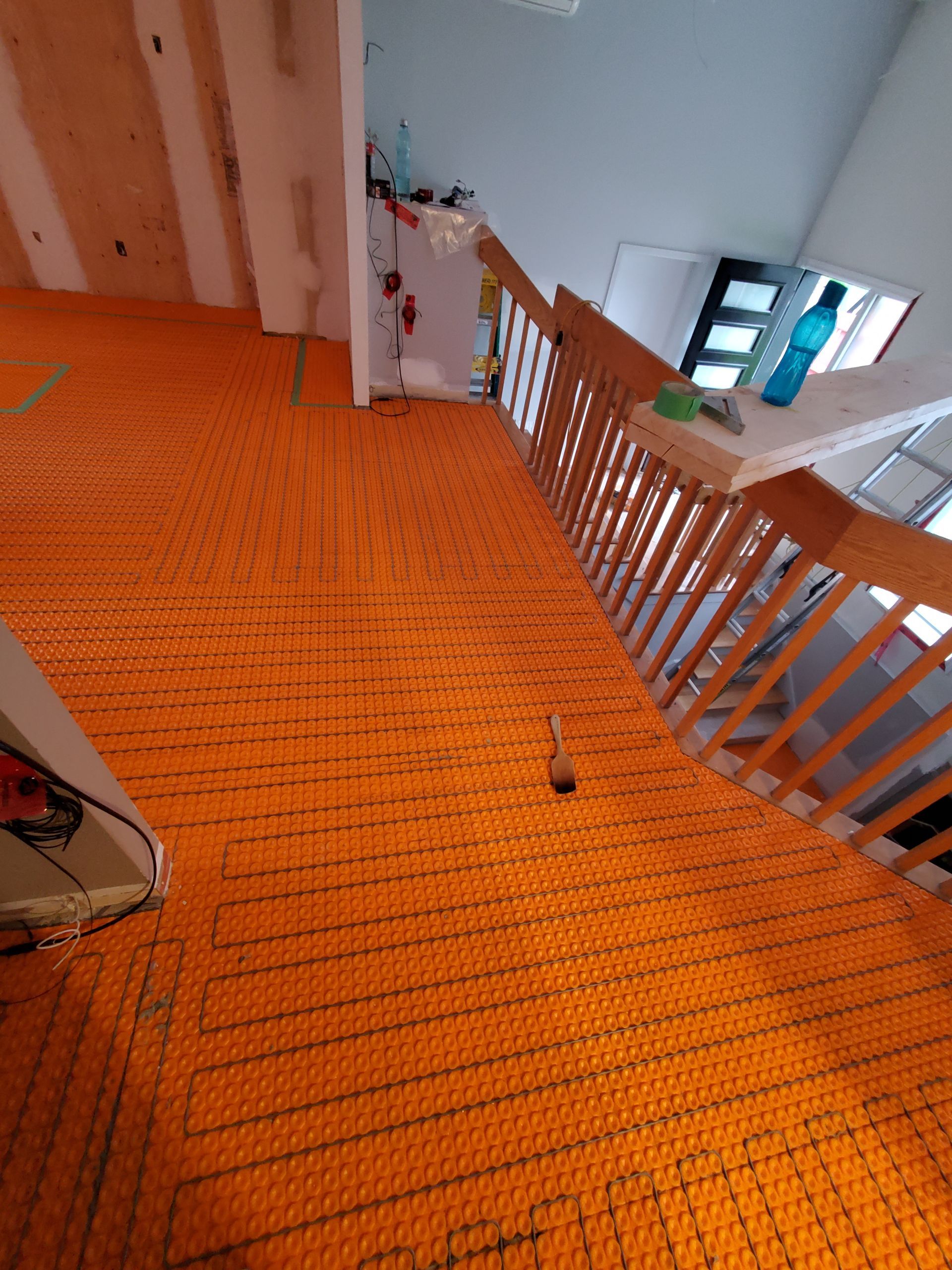 Un escalier avec une rampe en bois et un sol orange.