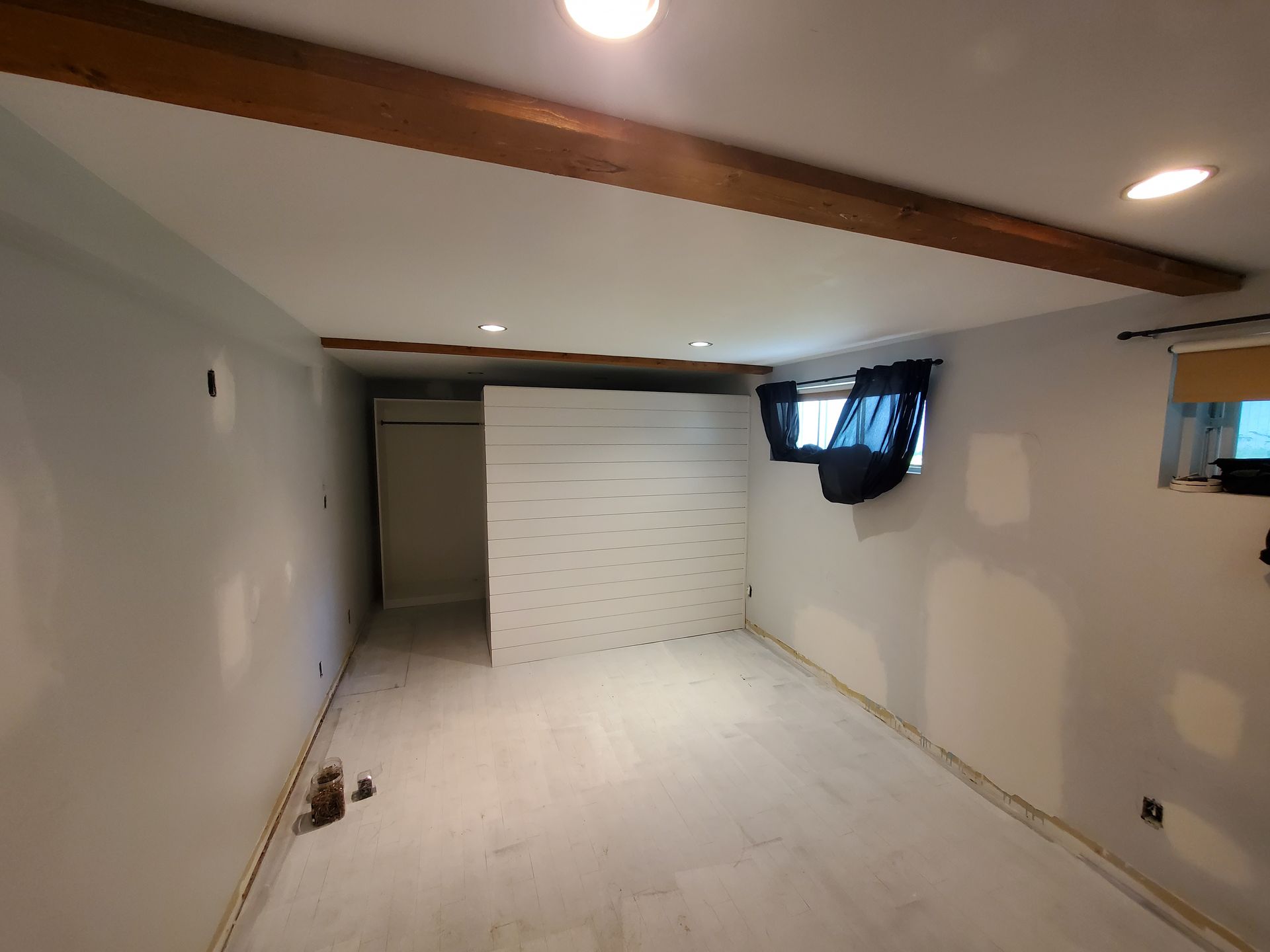 Une pièce vide avec des murs blancs et des poutres en bois.