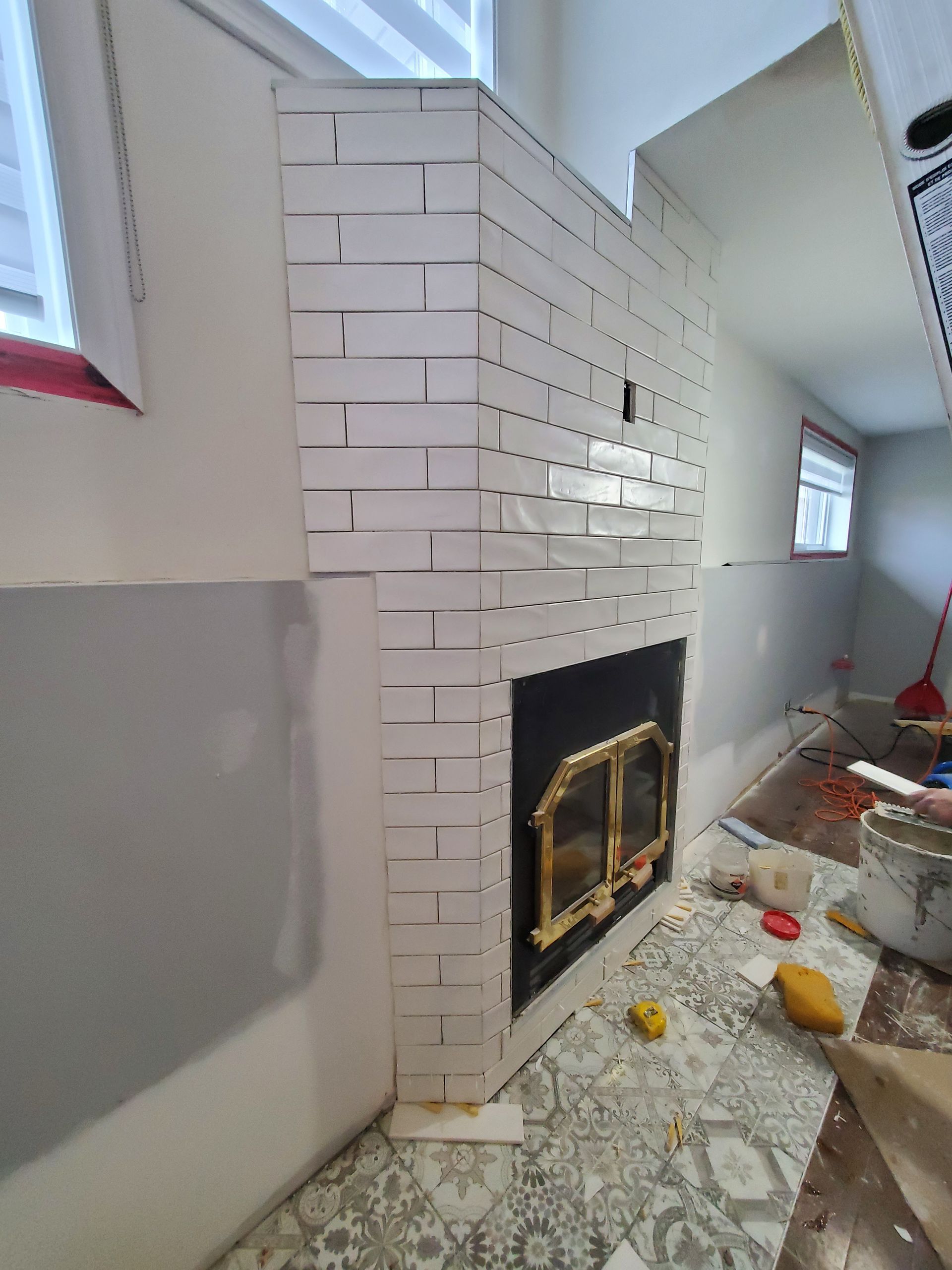 Une cheminée carrelée blanche est en cours de construction dans un salon.