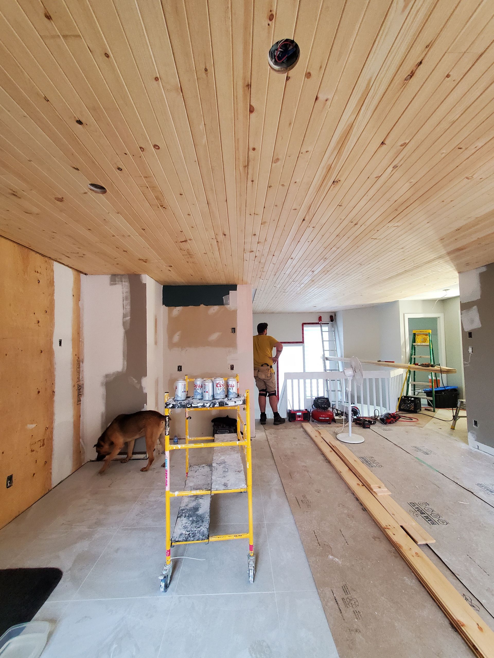 Un homme peint un plafond en bois dans une pièce.