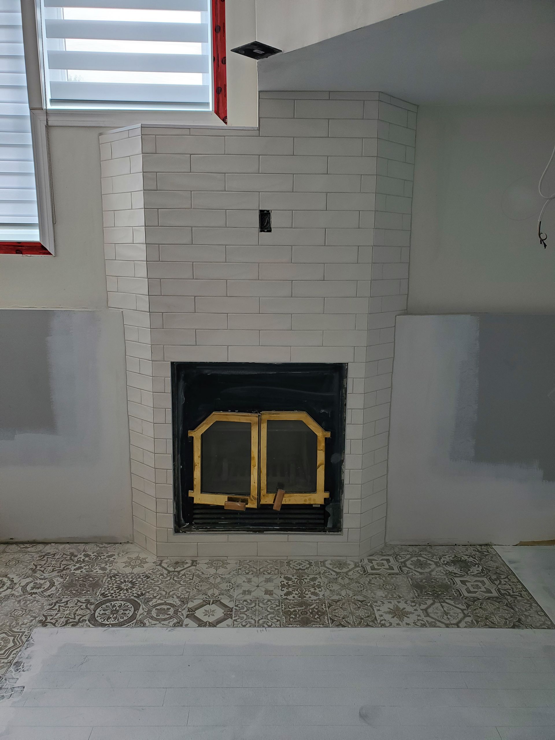 Une cheminée en brique blanche avec une porte noire dans un salon.