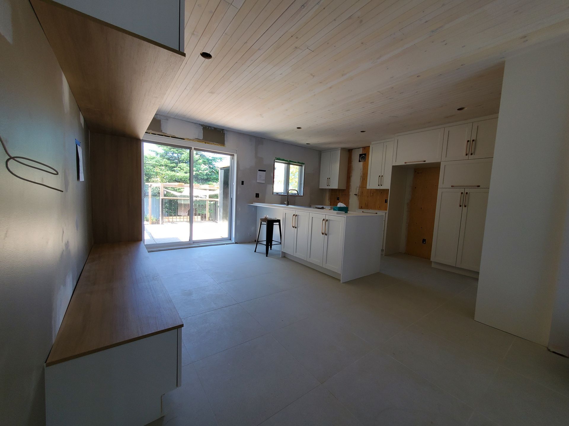 Une cuisine avec un plafond en bois et des armoires blanches