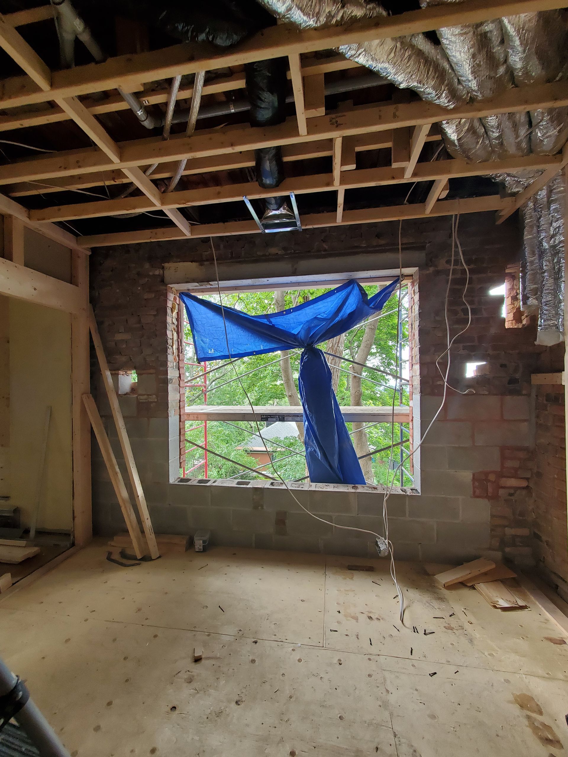 Une pièce en construction avec une bâche bleue suspendue au plafond.