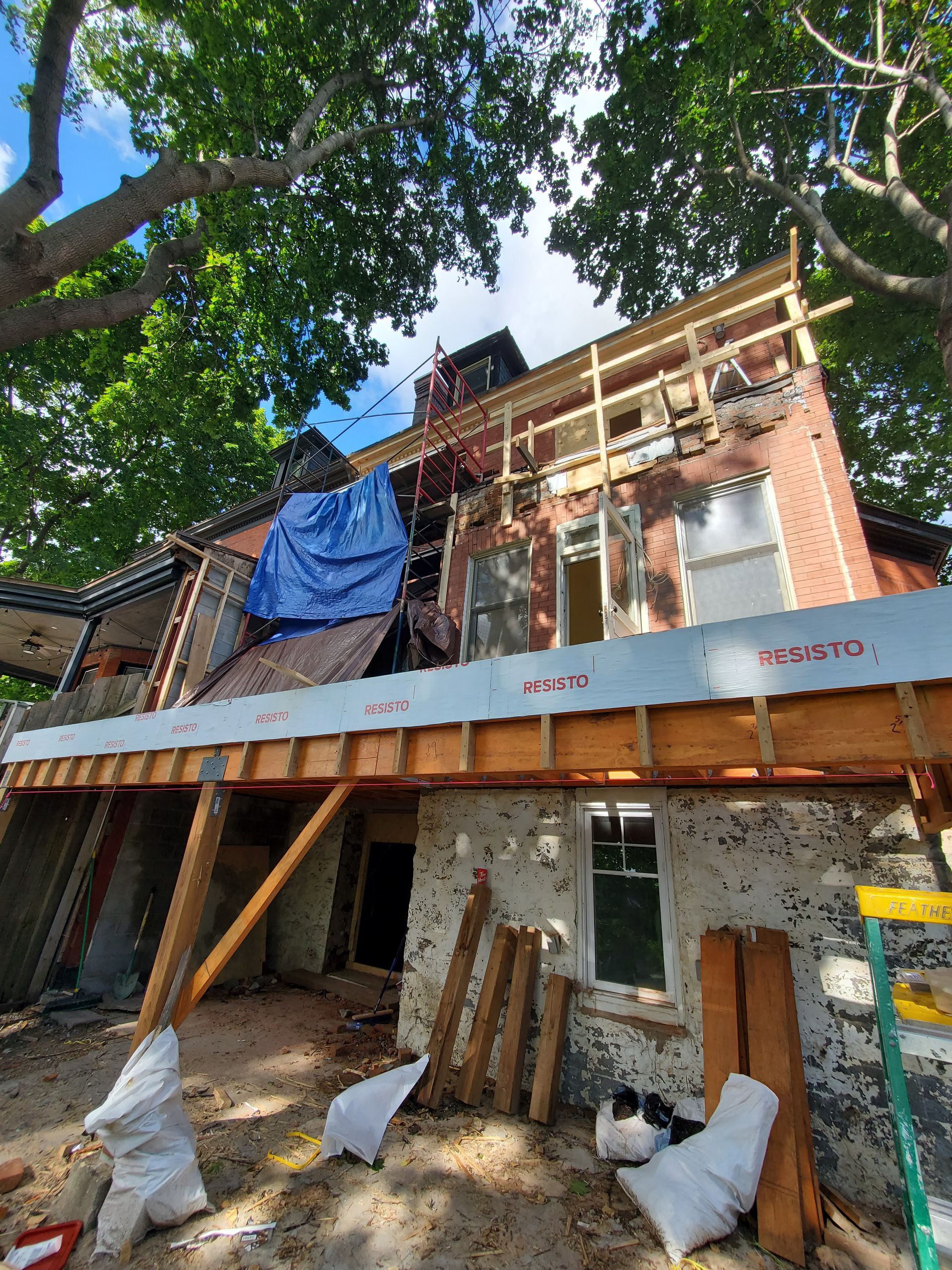 Un grand bâtiment en brique est en cours de rénovation avec une terrasse en bois.