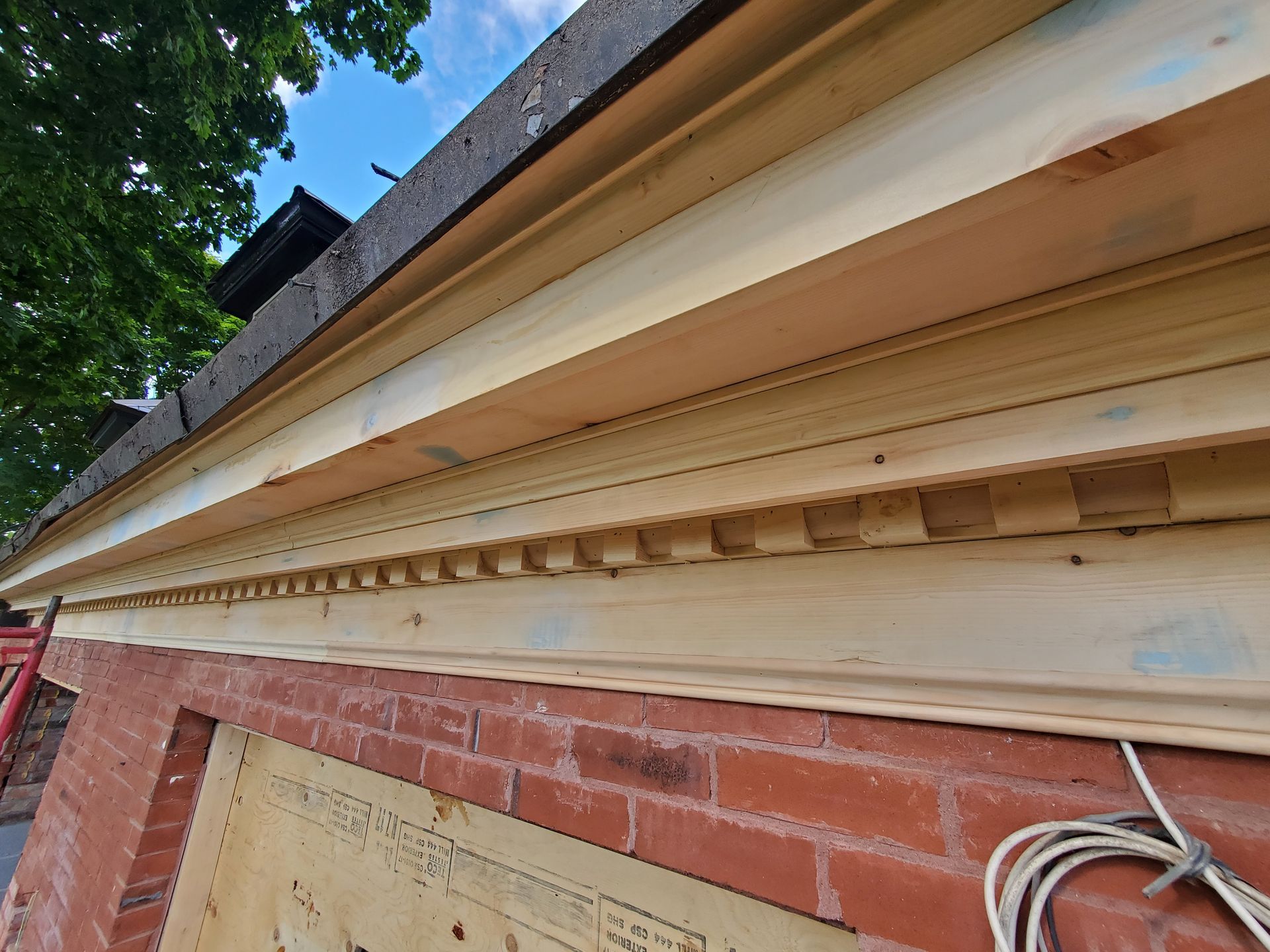 Une boiserie est en cours d'installation sur un bâtiment en brique.