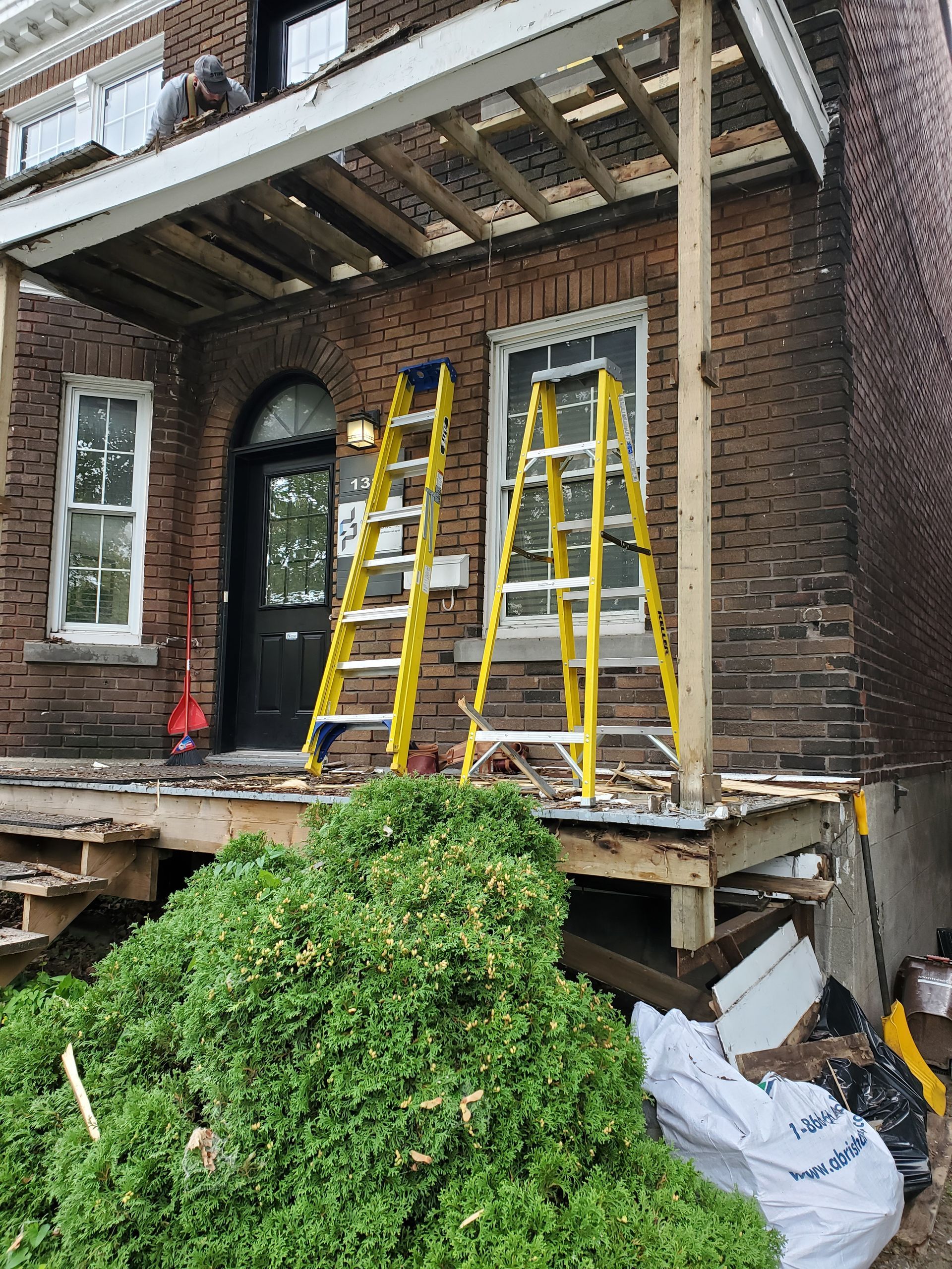 Deux échelles se trouvent sur le porche d'une maison en brique.