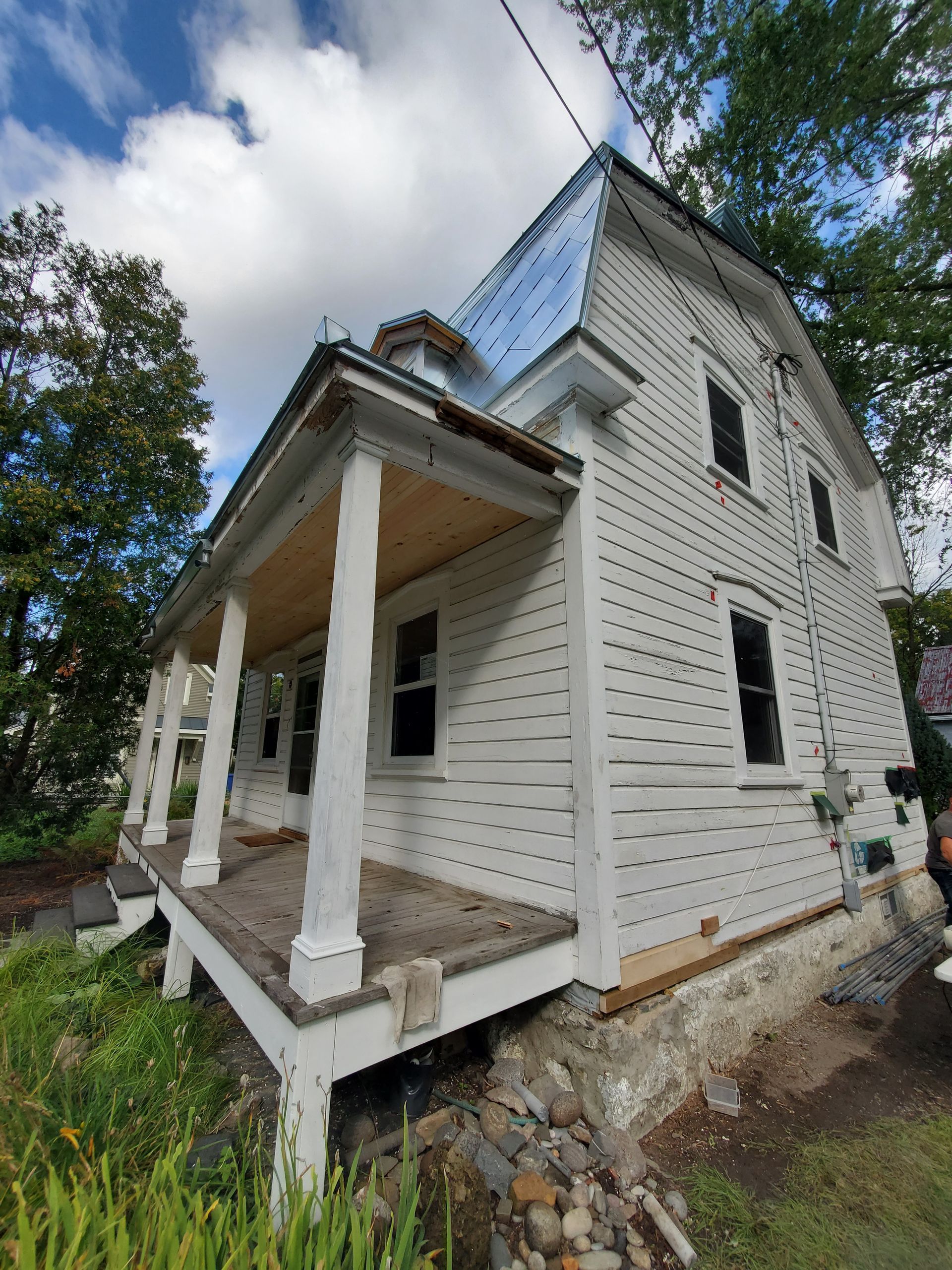 Une maison blanche avec un porche est en cours de rénovation.