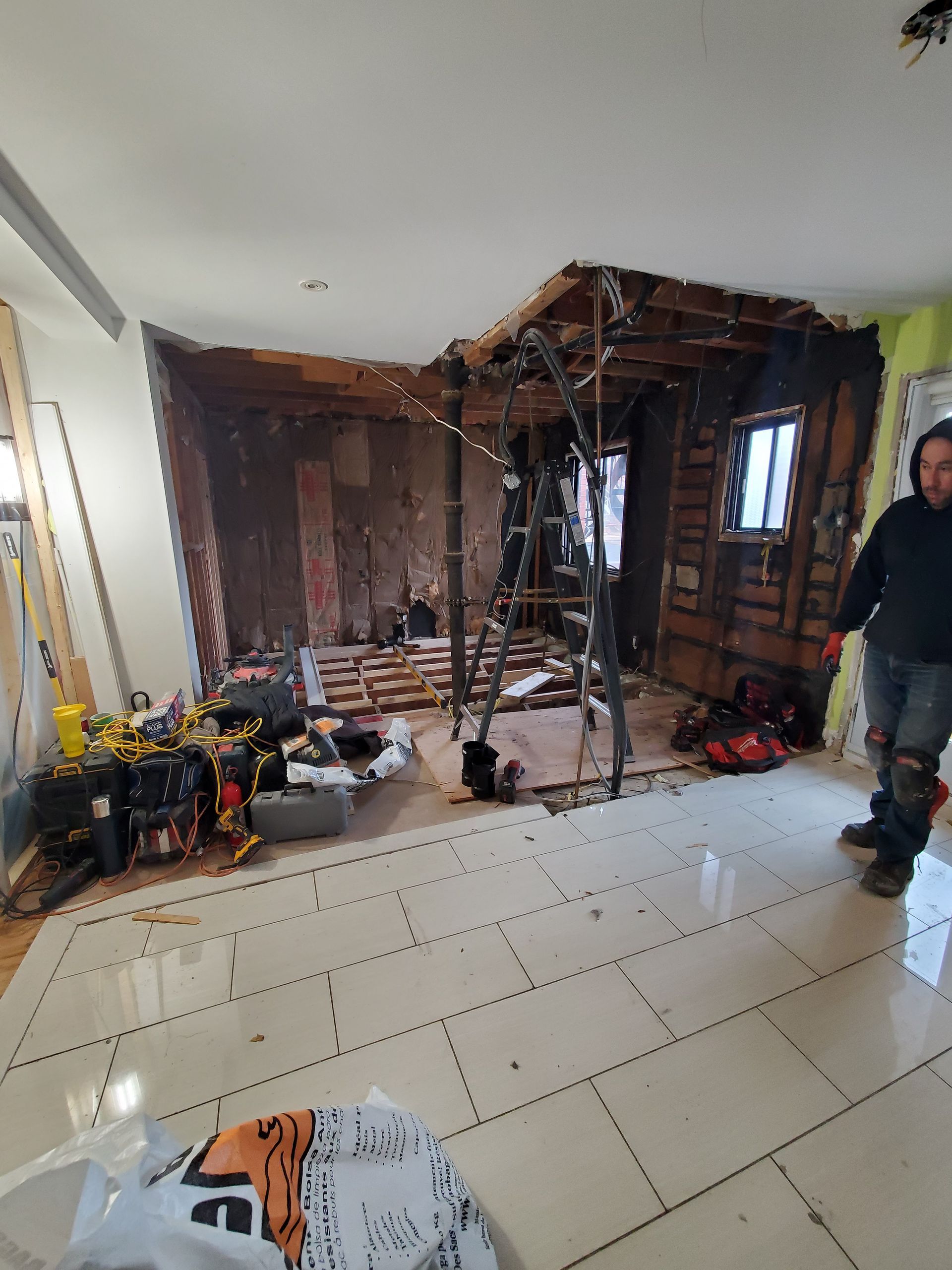 Un homme se tient dans une pièce avec un trou dans le plafond.
