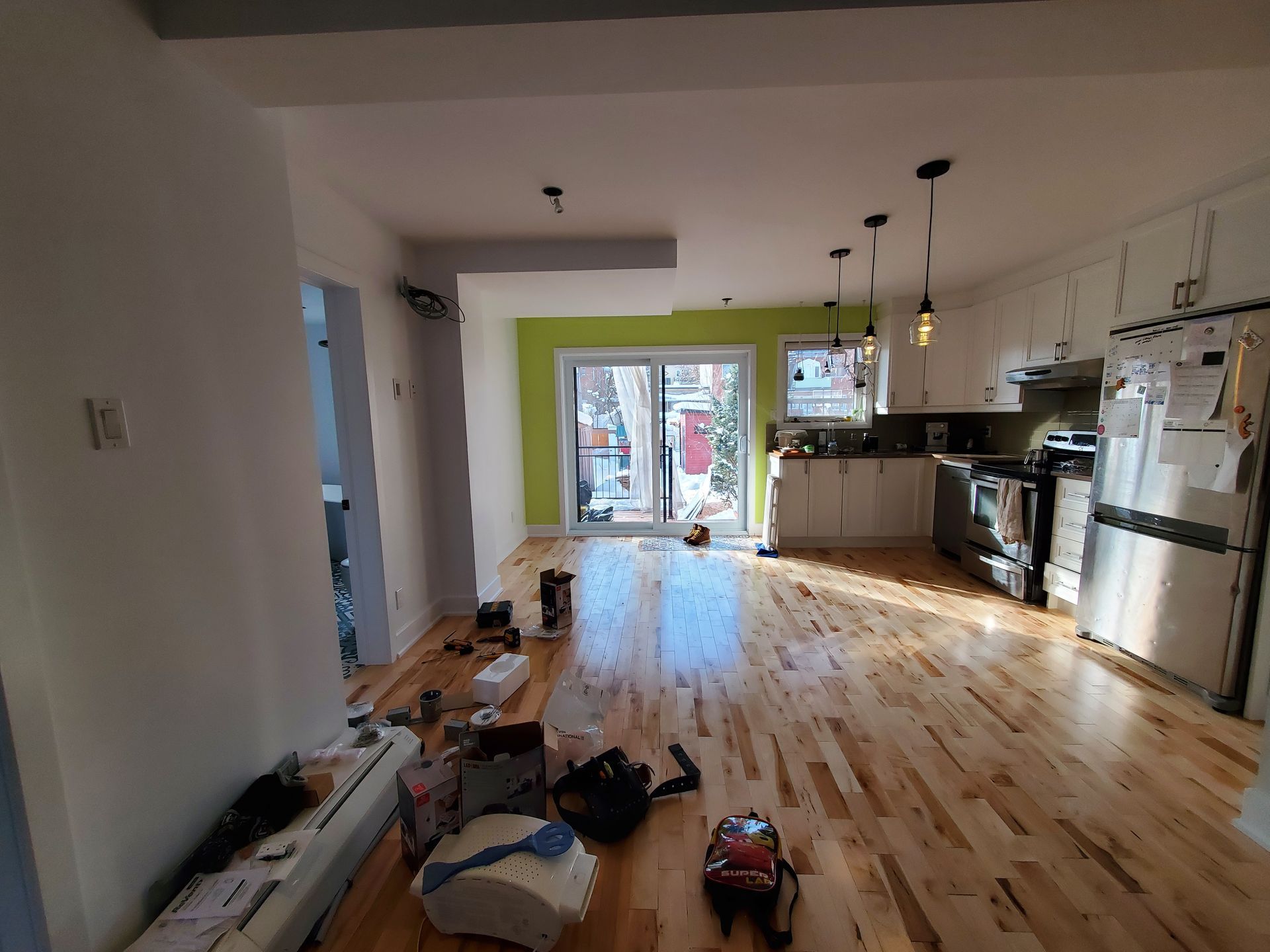 Une cuisine avec parquet et armoires blanches est en cours de rénovation.