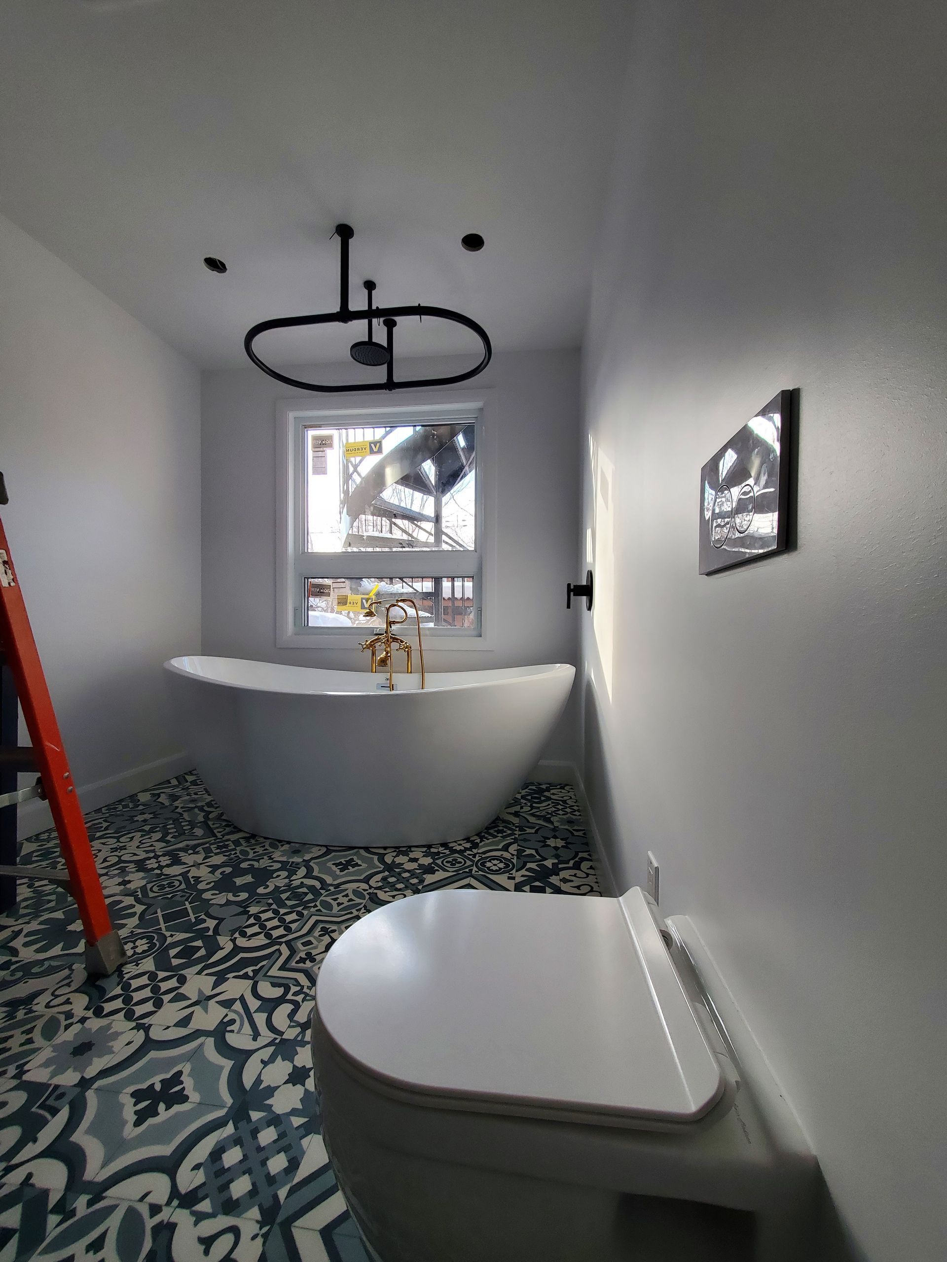 Une salle de bain avec baignoire , WC et échelle.