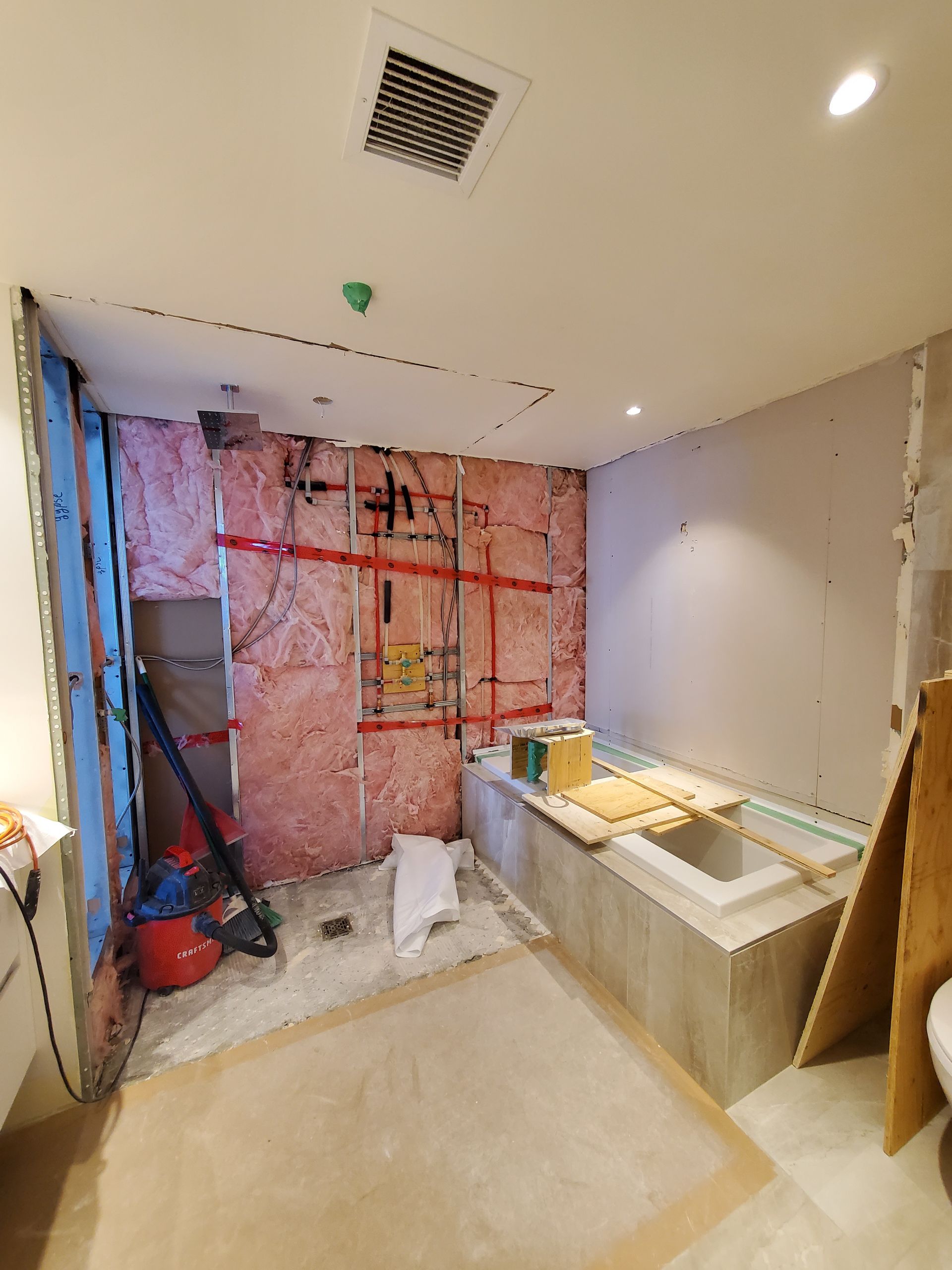 Une salle de bain en construction avec une baignoire et un aspirateur.