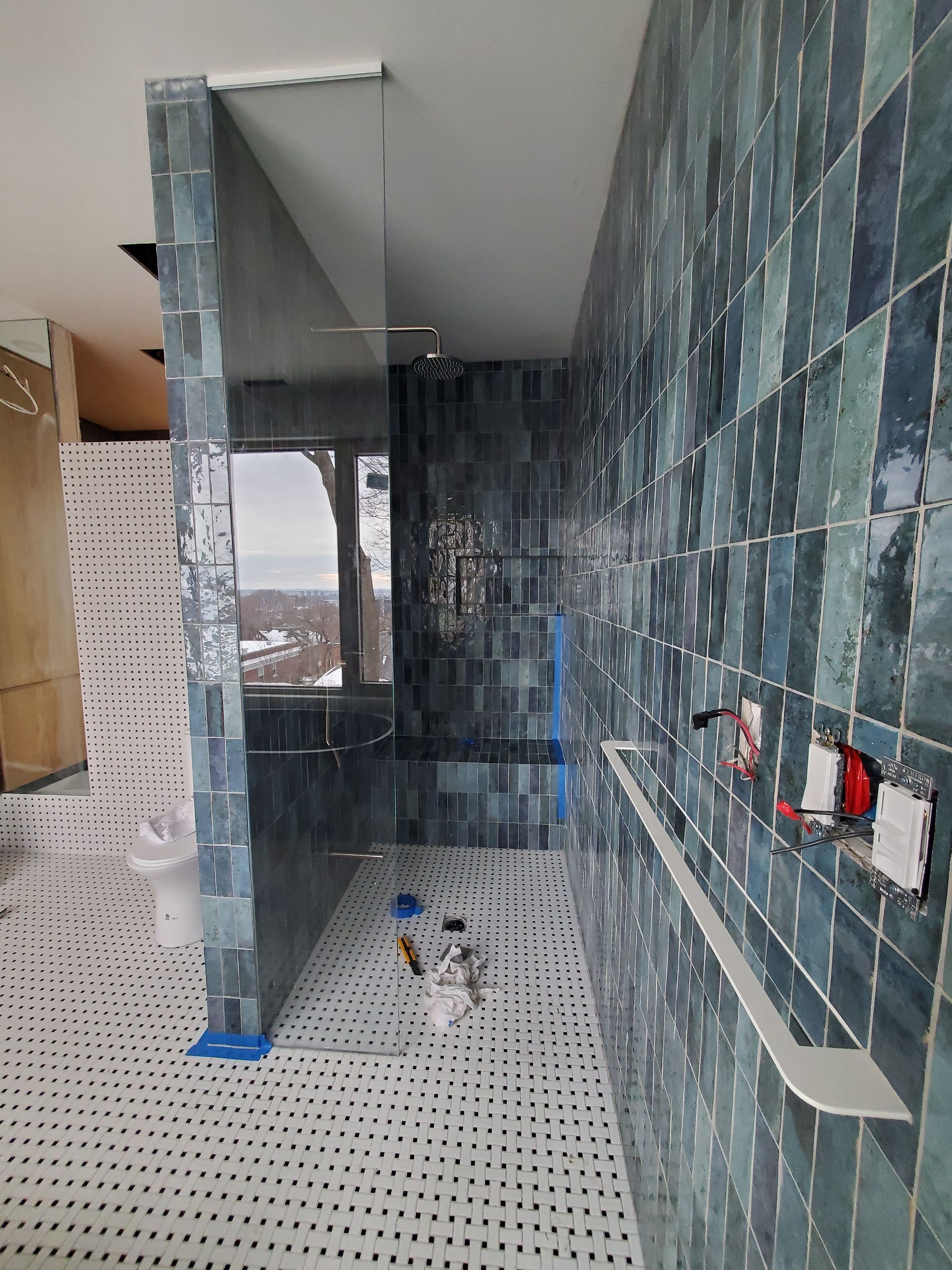 Une salle de bain avec carrelage bleu et douche à l'italienne.