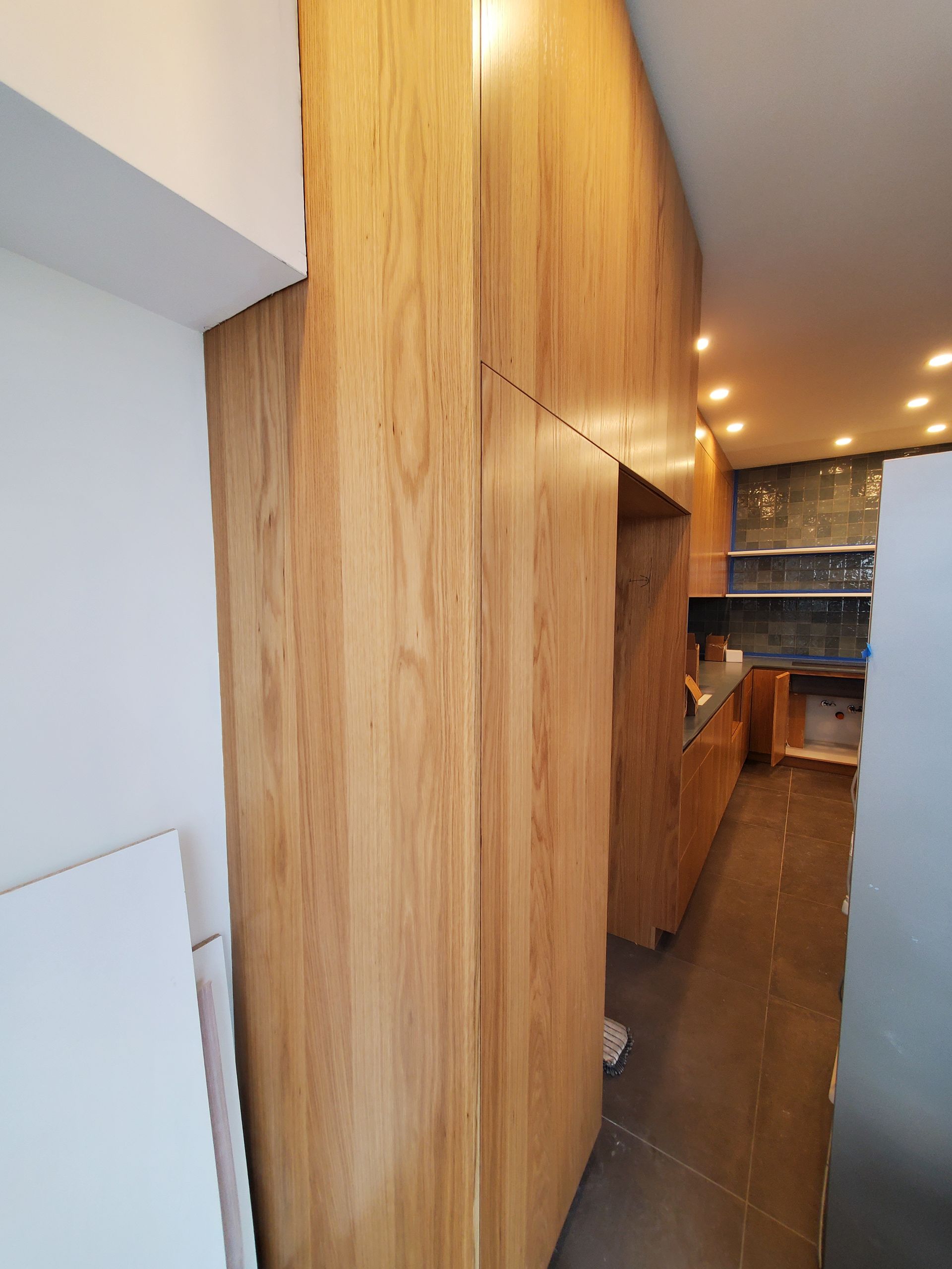 Une cuisine avec armoires en bois et mur en bois.