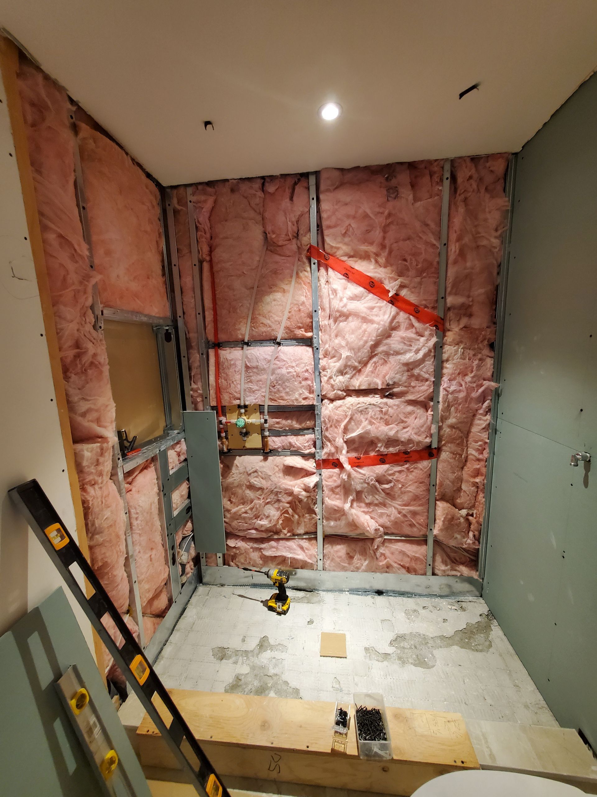 Une salle de bain est en cours de rénovation avec une isolation rose et un WC.