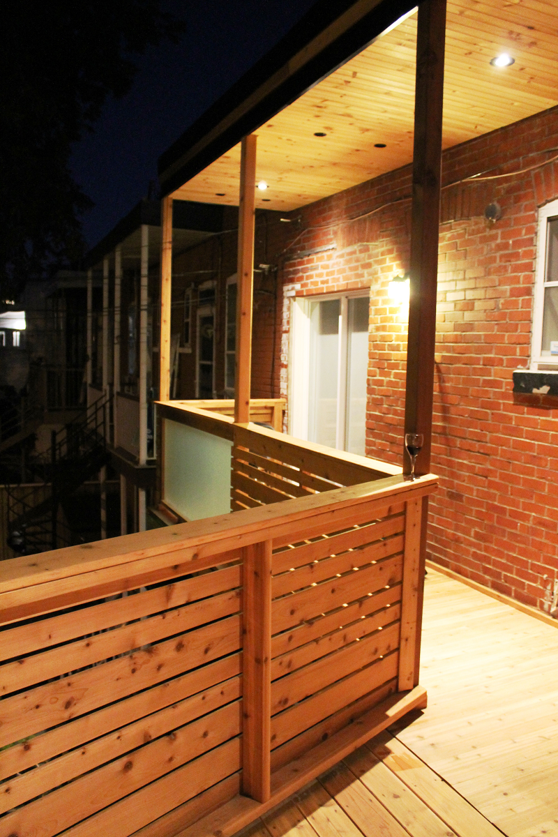 Un balcon en bois avec un mur de briques en arrière-plan