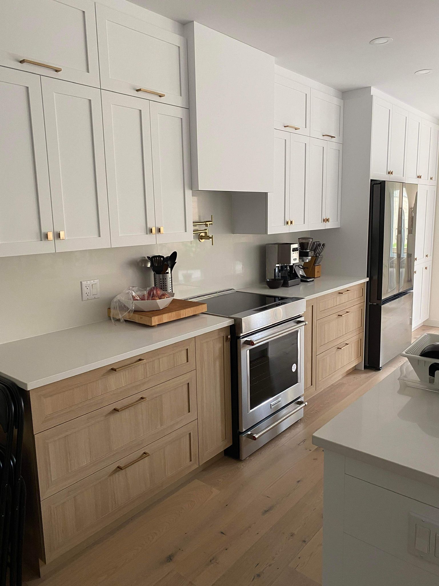 Une cuisine avec des armoires blanches, des armoires en bois, une cuisinière et un réfrigérateur.