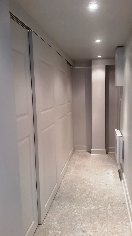 Un long couloir avec des portes coulissantes et un radiateur.