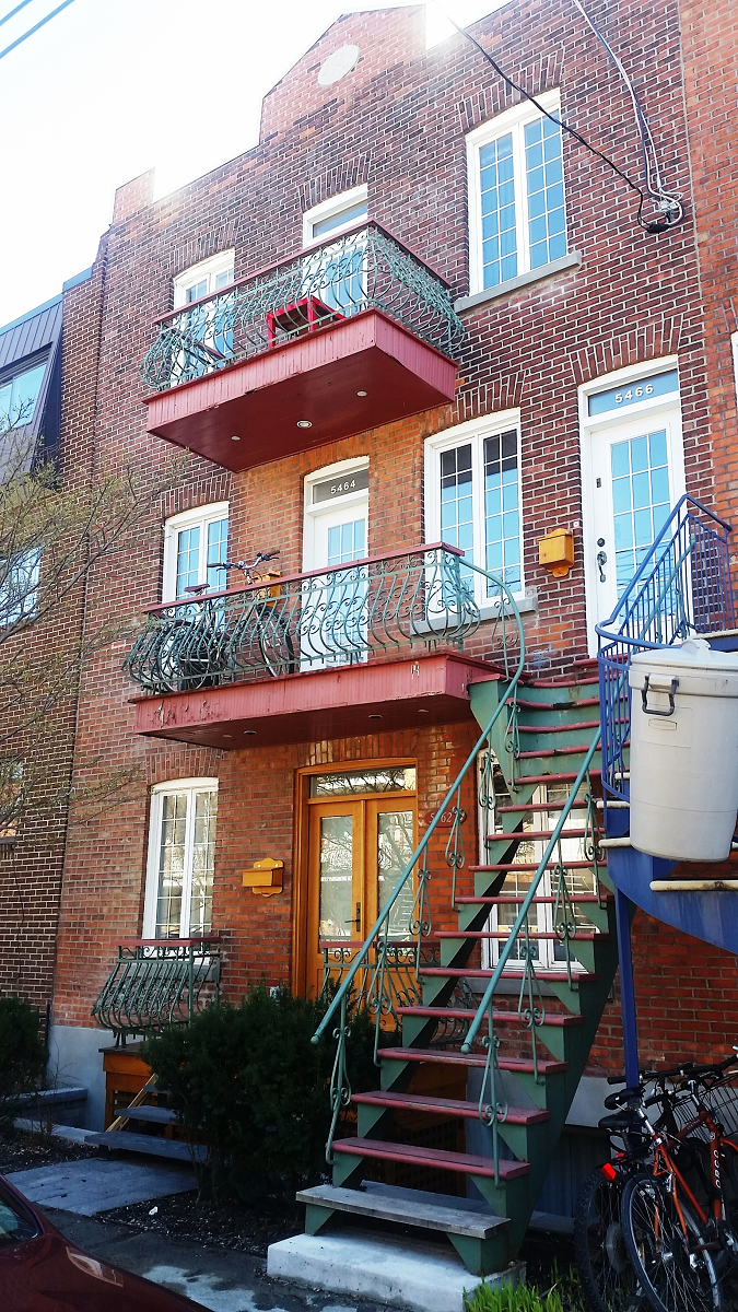 Un immeuble en brique avec des escaliers menant au deuxième étage et des balcons.