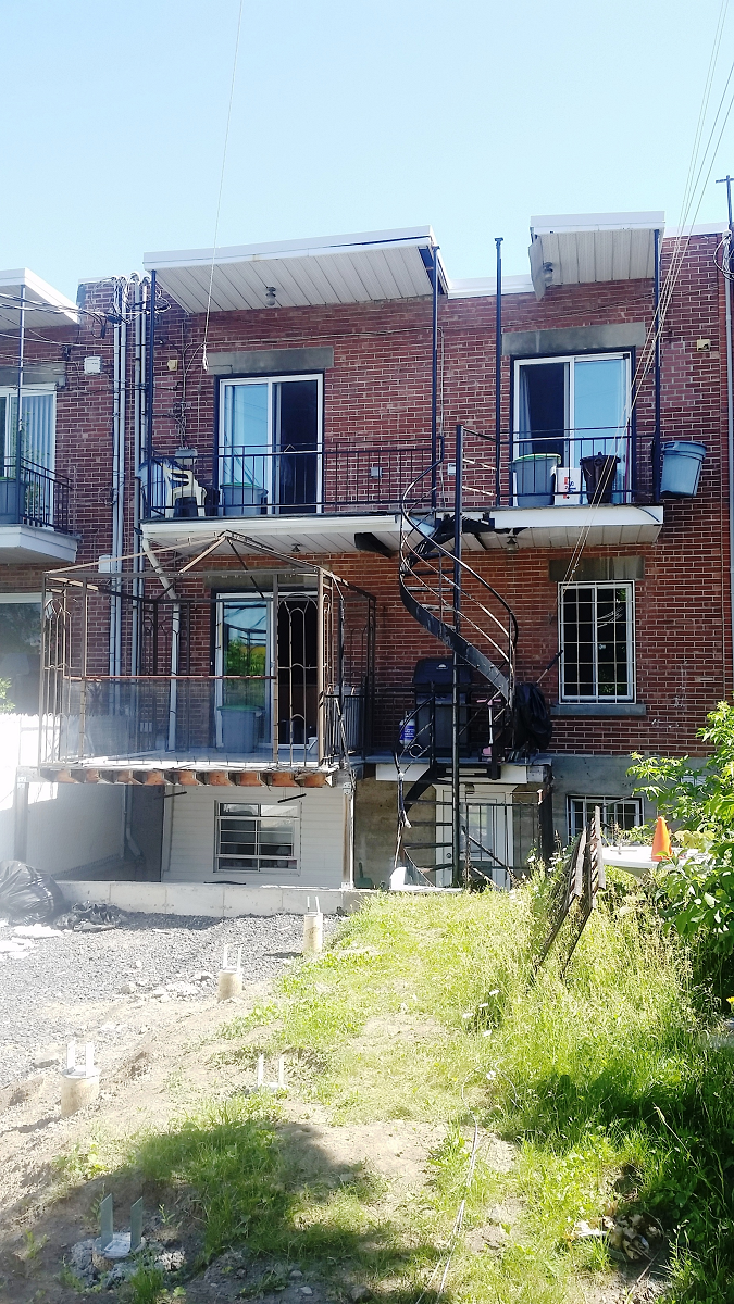 L'arrière d'un immeuble en brique avec balcons et escaliers.