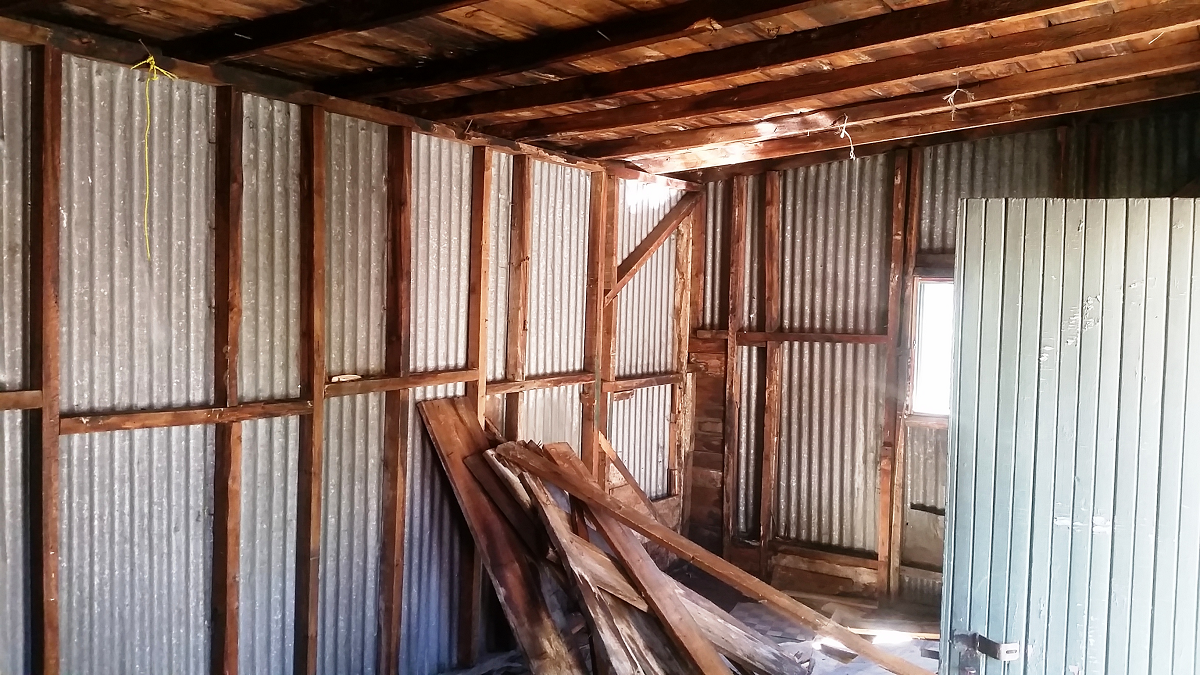 Une pièce avec poutres en bois et murs en tôle ondulée.