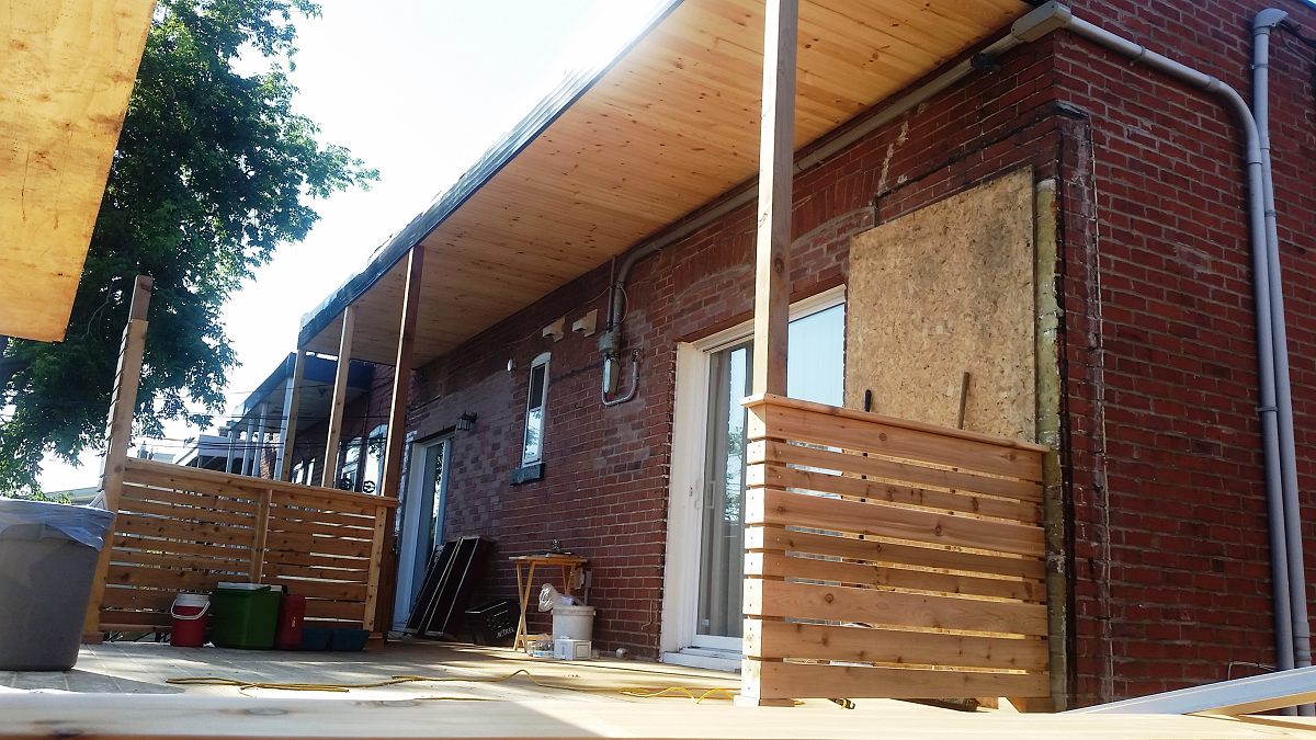 Un bâtiment en brique avec une clôture en bois et un porche