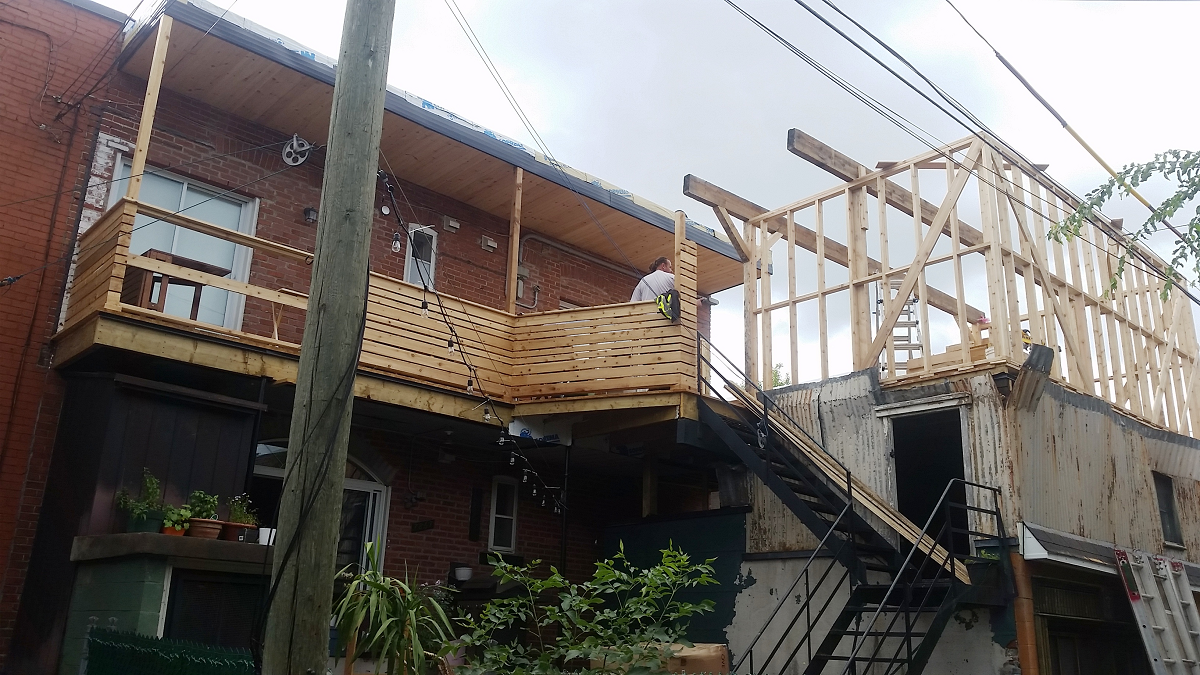 Un bâtiment en construction avec une terrasse et des escaliers en bois.