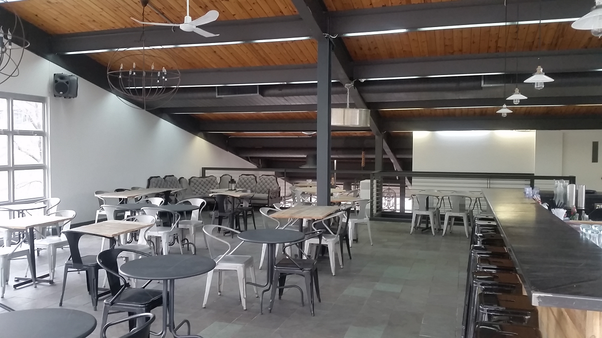 Une grande salle avec tables et chaises et un bar
