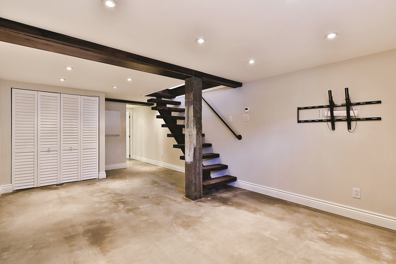 Un sous-sol vide avec un escalier menant au deuxième étage.