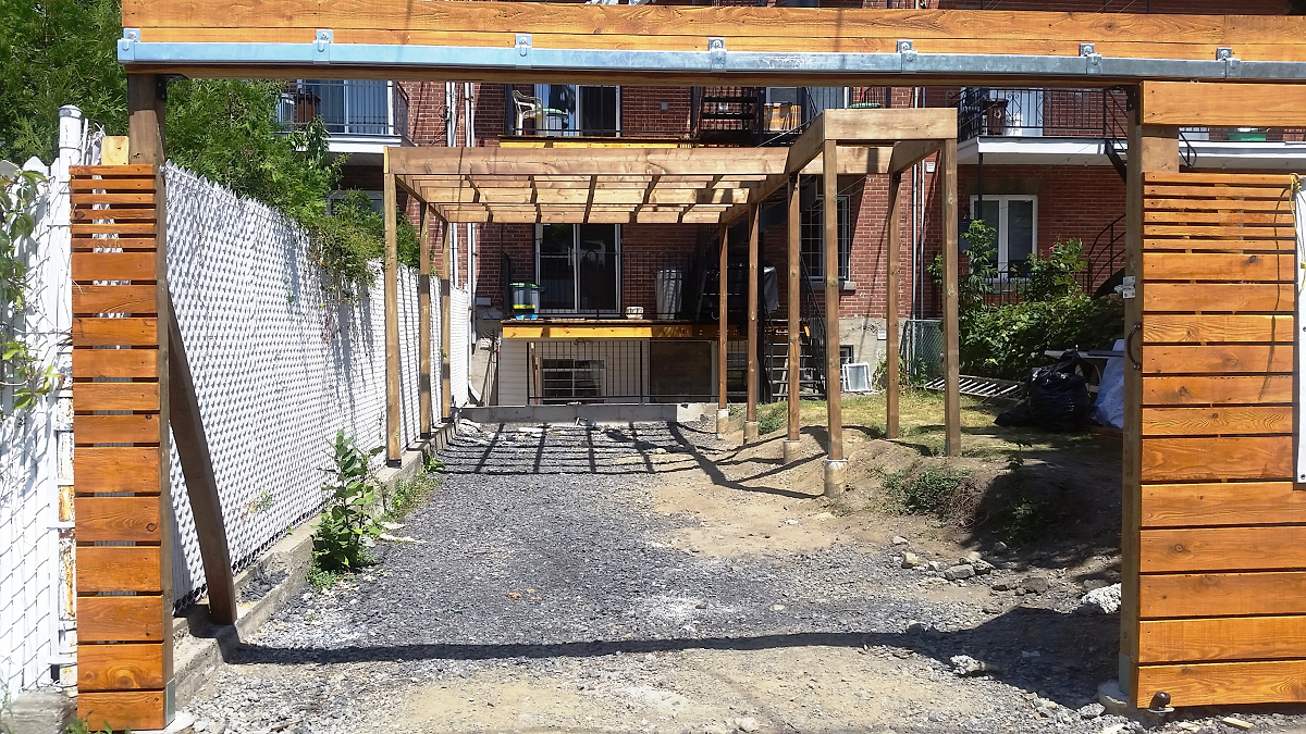 Une structure en bois est en cours de construction devant un bâtiment en brique.