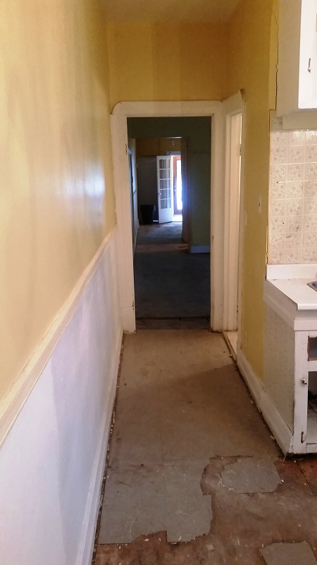 Un long couloir menant à une cuisine dans une maison vide.
