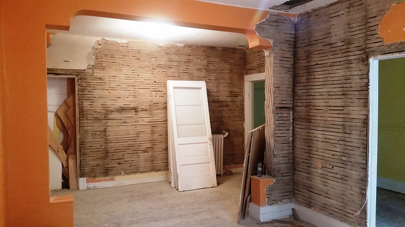 Une pièce avec un mur de briques et une porte blanche.