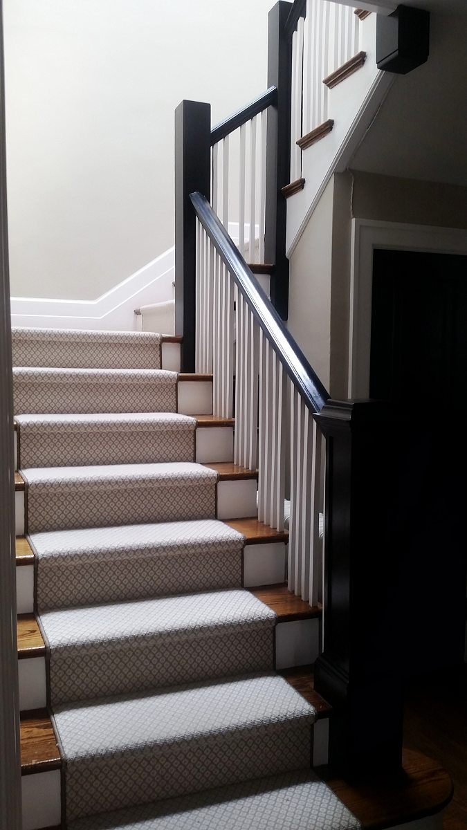 Un escalier avec un tapis blanc et une rampe noire