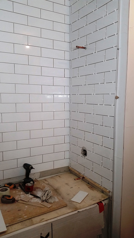Une salle de bain avec des murs en briques blanches et un parquet en bois.