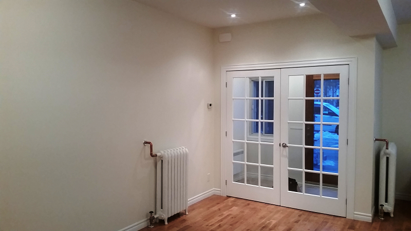 Une pièce vide avec un radiateur et des portes françaises.