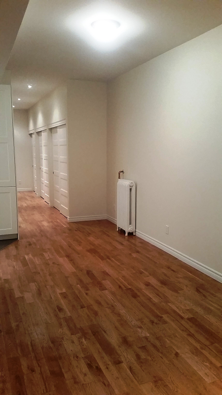 Une pièce vide avec du parquet et des murs blancs.