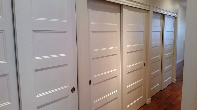 Une rangée de portes coulissantes blanches dans un couloir.