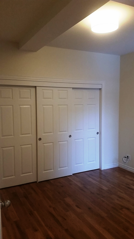 Une pièce vide avec des portes coulissantes et du parquet.