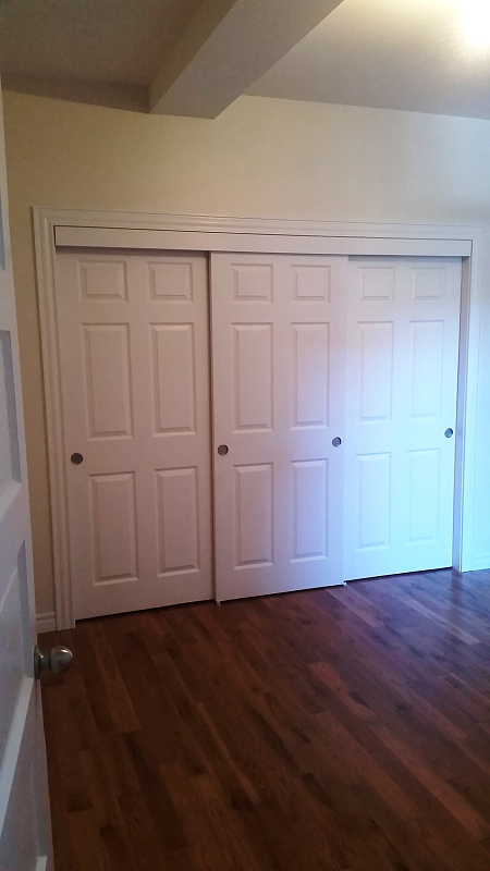 Une chambre avec portes coulissantes et parquet.