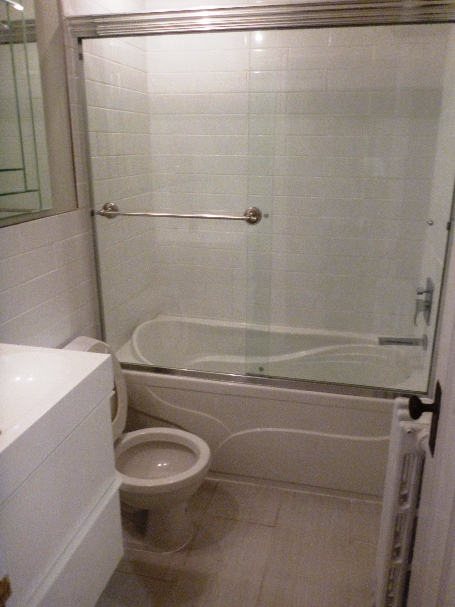 Une salle de bain avec WC une baignoire et une porte coulissante vitrée