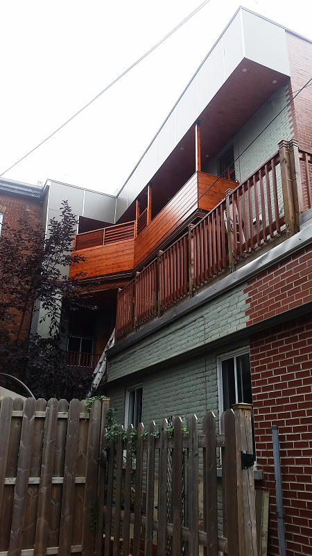 Un bâtiment en brique avec une terrasse en bois et une clôture en bois devant.