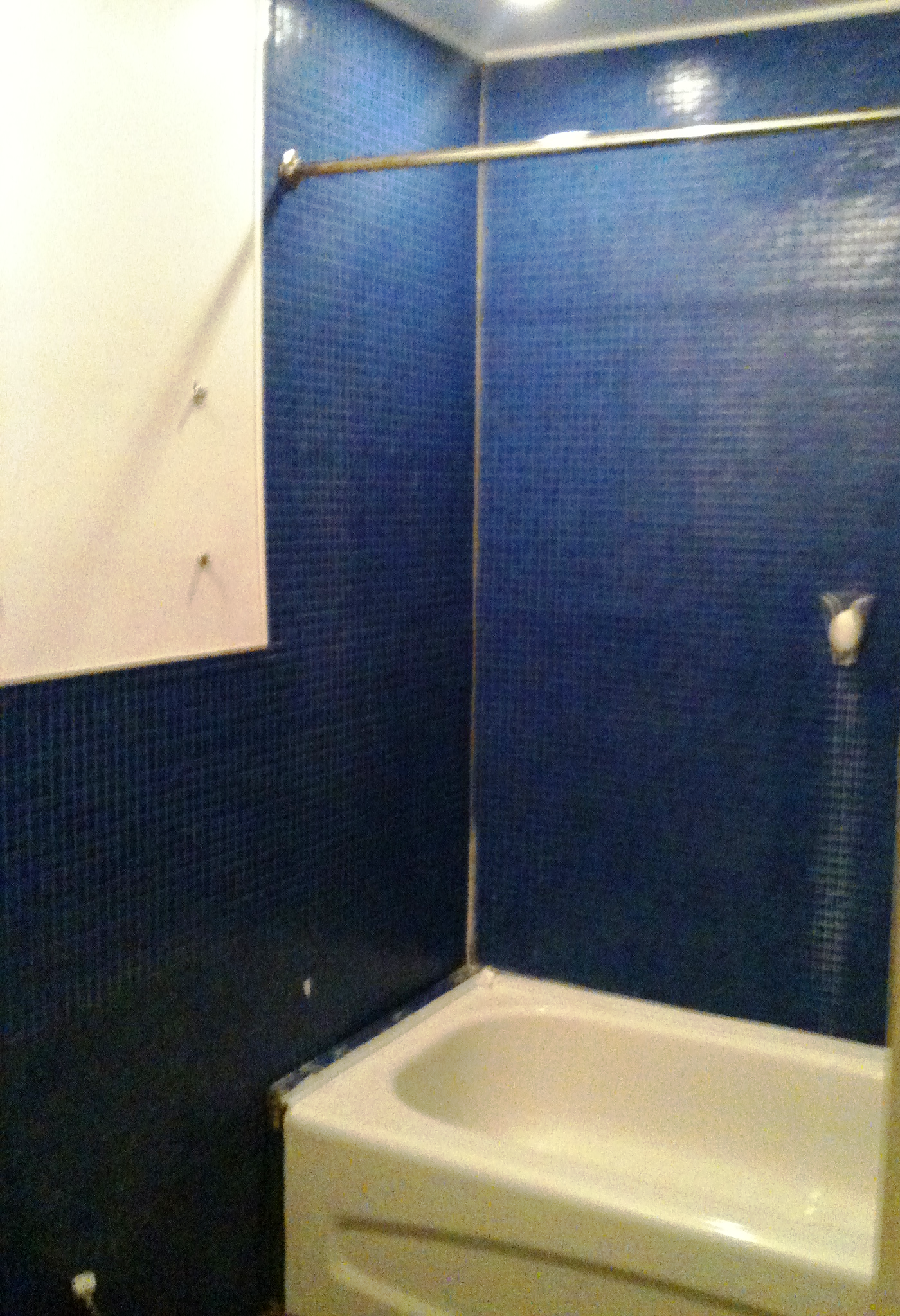 Une salle de bain avec carrelage bleu et baignoire.