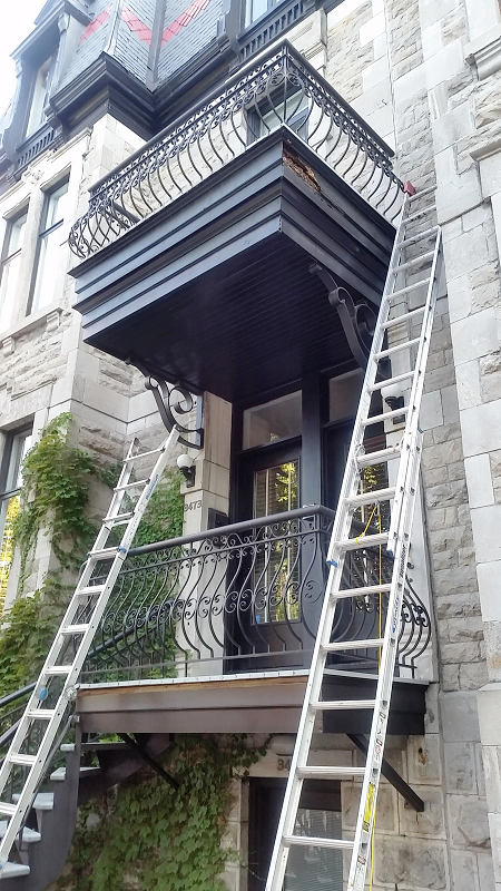 Un balcon sur le côté d'un immeuble auquel est attachée une échelle.