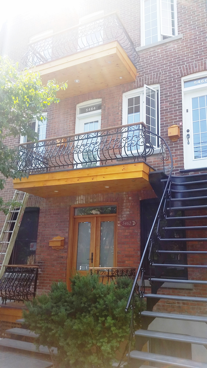 Un bâtiment en brique avec des escaliers qui y mènent et un balcon.