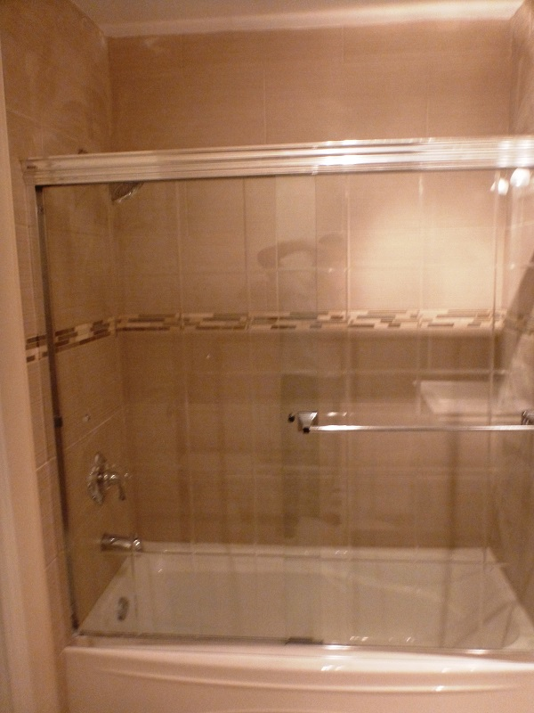 Une salle de bain avec baignoire et porte de douche coulissante en verre.