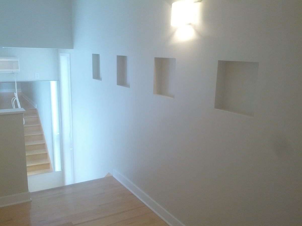 Un couloir avec des escaliers et une lumière au mur