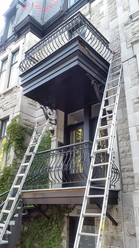 Un balcon sur le côté d'un immeuble auquel est attachée une échelle.